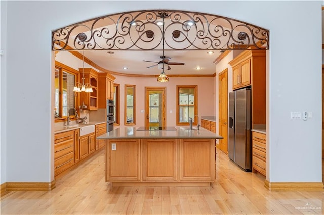 kitchen with a kitchen island with sink, sink, stainless steel appliances, and light hardwood / wood-style flooring