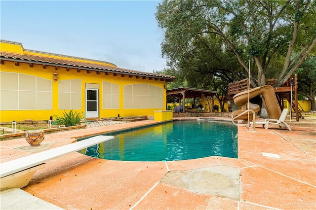 view of pool with a diving board and a patio area