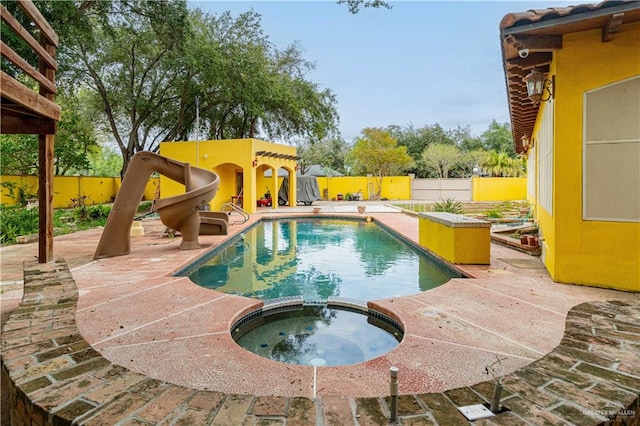 view of pool with an in ground hot tub, a patio area, and a water slide