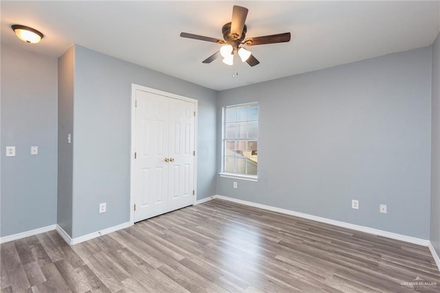 unfurnished bedroom featuring ceiling fan, wood-type flooring, and a closet