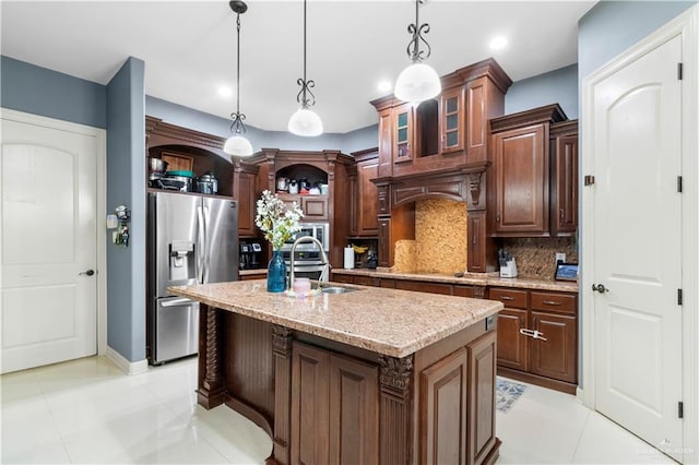 kitchen with decorative backsplash, stainless steel refrigerator with ice dispenser, a kitchen island with sink, and hanging light fixtures