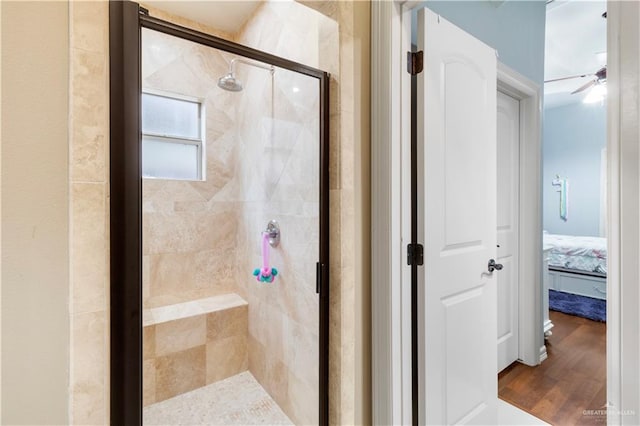 bathroom with wood-type flooring, ceiling fan, and a shower with shower door