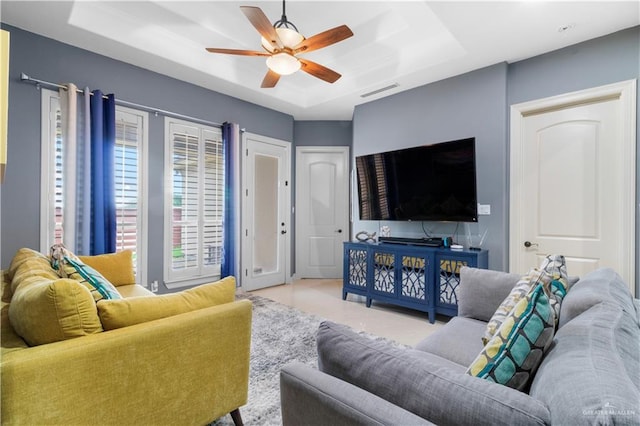 living room featuring a raised ceiling and ceiling fan