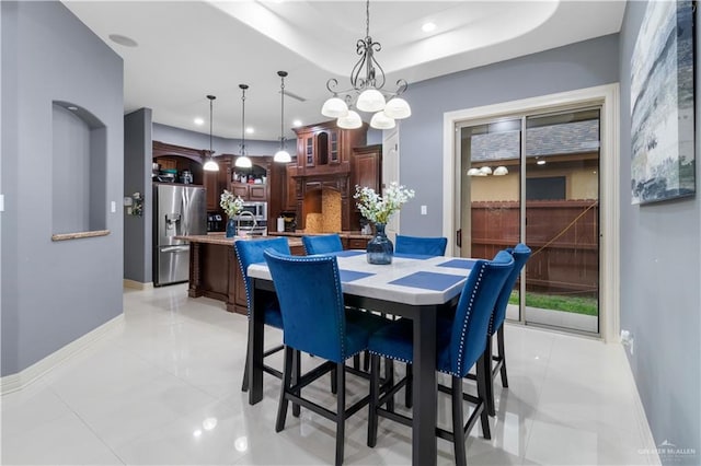 dining area featuring a raised ceiling, light tile patterned floors, and a chandelier