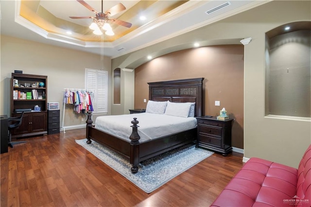 bedroom with a tray ceiling, ceiling fan, crown molding, and dark wood-type flooring