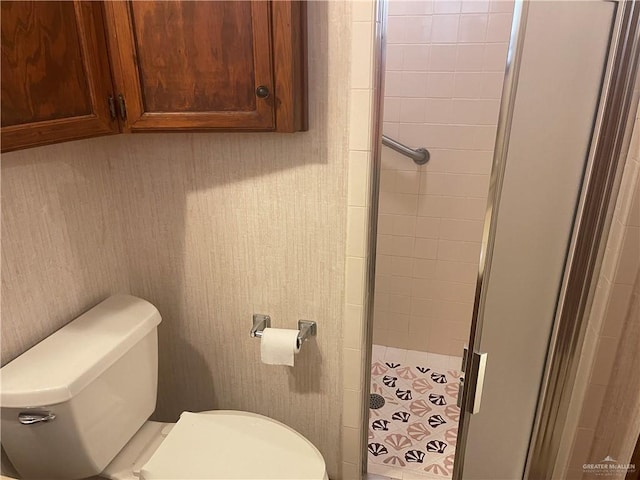 bathroom with toilet and a shower with door