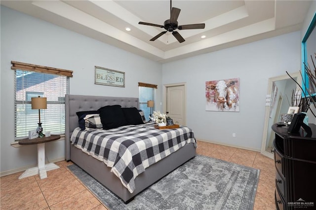 bedroom featuring light tile patterned floors, a tray ceiling, and baseboards