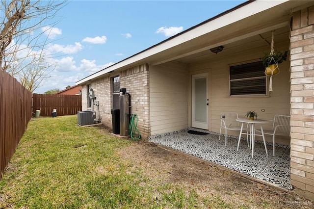 exterior space featuring central AC, brick siding, a yard, and a fenced backyard