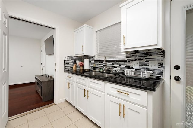 kitchen with light tile patterned floors, a sink, and white cabinetry