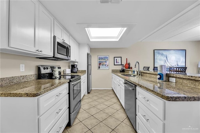 110 Verna Jean Dr Unit 110, South Padre Island, TX 78597 - kitchen with appliances with stainless steel finishes, a peninsula, white cabinetry, light tile patterned floors, and dark stone countertops