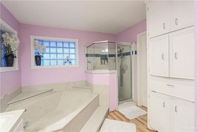 bathroom featuring a bath, a shower stall, and wood finished floors