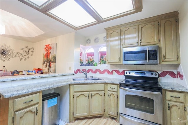 kitchen with decorative backsplash, appliances with stainless steel finishes, light stone countertops, and a sink