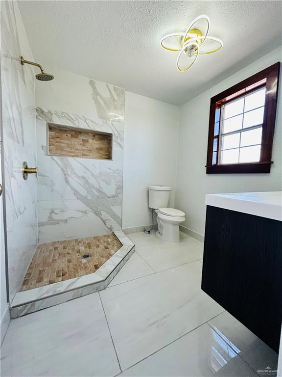 612 E Tom Landry St, Mission, TX 78572 - full bathroom with a textured ceiling, a marble finish shower, and vanity