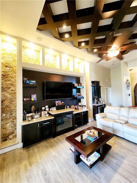 living room with coffered ceiling, ceiling fan, beam ceiling, and light hardwood / wood-style flooring