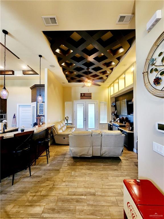 living room featuring french doors, a towering ceiling, light hardwood / wood-style flooring, and ceiling fan