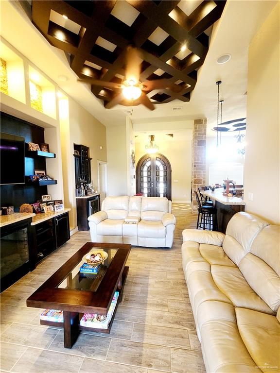 living room featuring ceiling fan, coffered ceiling, and a high ceiling