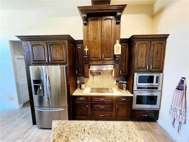 kitchen with appliances with stainless steel finishes, light wood-type flooring, tasteful backsplash, and dark brown cabinetry