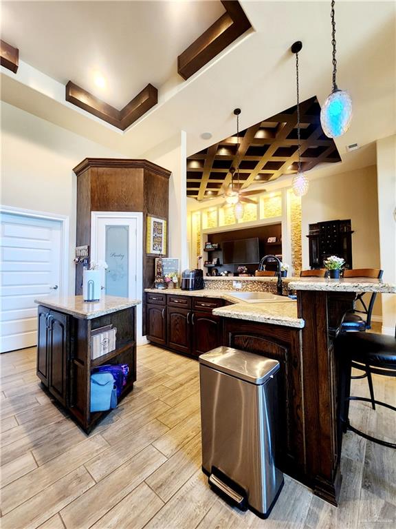 kitchen featuring decorative light fixtures, dark brown cabinetry, and light hardwood / wood-style flooring