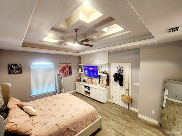 bedroom featuring a tray ceiling, ceiling fan, and light wood-type flooring