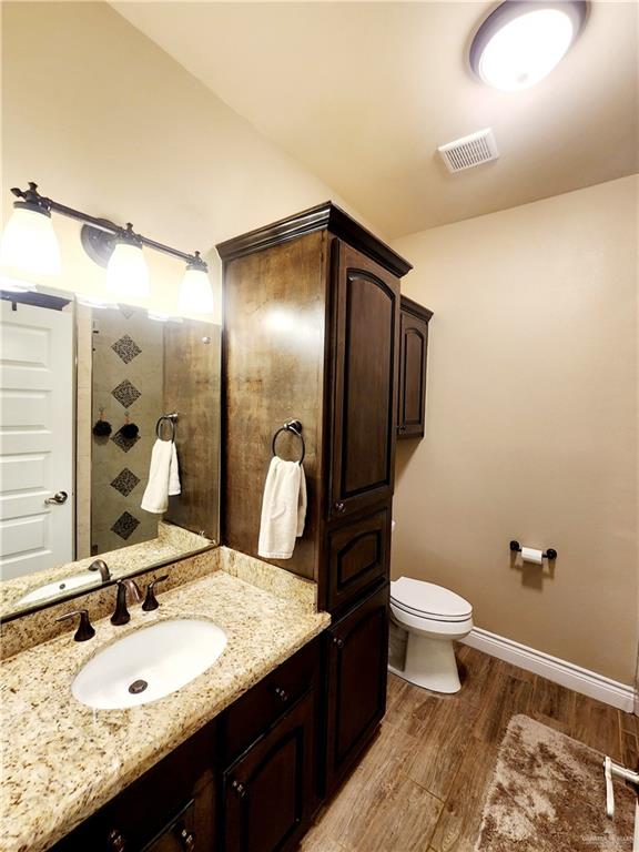 bathroom with hardwood / wood-style floors, vanity, and toilet