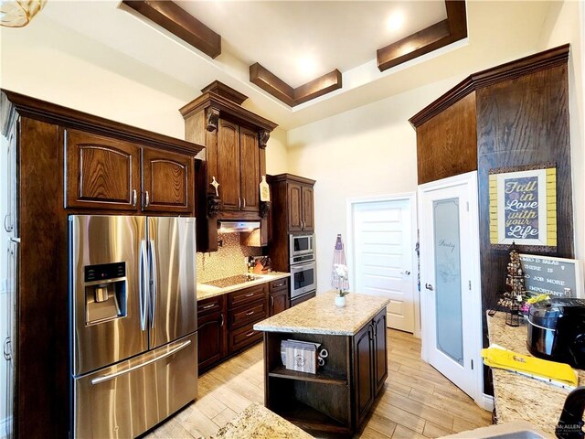 kitchen featuring appliances with stainless steel finishes, light hardwood / wood-style flooring, a kitchen island, and dark brown cabinets