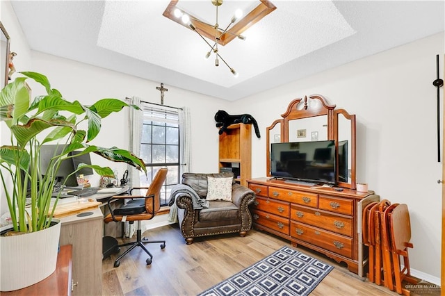 office space featuring a tray ceiling and light hardwood / wood-style floors