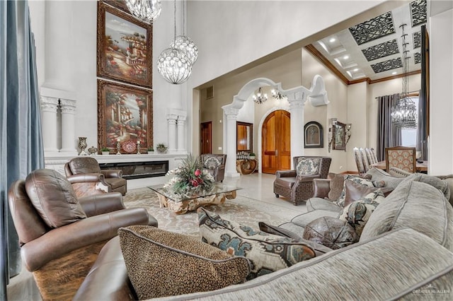 living room with a towering ceiling, coffered ceiling, a chandelier, and ornate columns