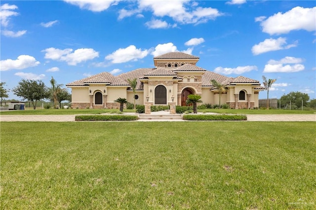 mediterranean / spanish-style home with a front lawn, stucco siding, and a tiled roof