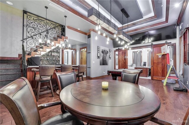 dining room featuring stairs, wood-type flooring, crown molding, and a raised ceiling