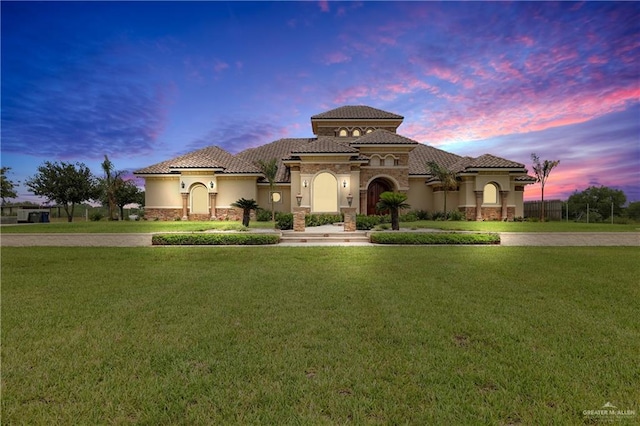 mediterranean / spanish home featuring a front lawn, stucco siding, and concrete driveway