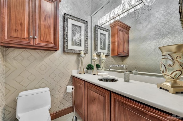 bathroom with tile patterned flooring, vanity, toilet, baseboards, and wallpapered walls