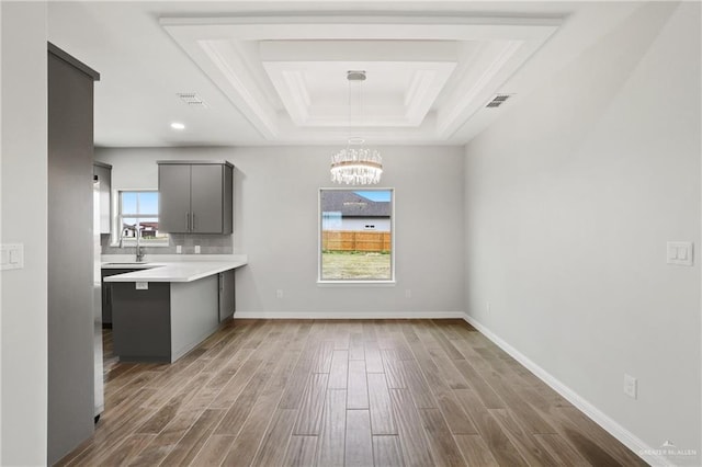 556 Candela St, Edinburg, TX 78542 - unfurnished dining area featuring a tray ceiling, wood finished floors, a chandelier, and ornamental molding