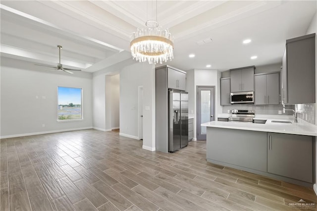 556 Candela St, Edinburg, TX 78542 - kitchen with gray cabinets, stainless steel appliances, open floor plan, a tray ceiling, and a peninsula