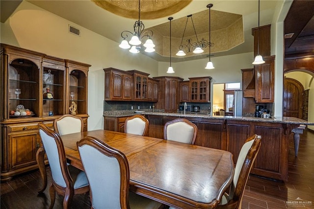 dining space featuring a raised ceiling, a towering ceiling, and an inviting chandelier