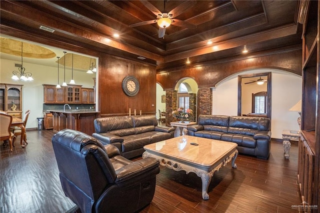 interior space with ceiling fan with notable chandelier, a raised ceiling, and dark wood-type flooring