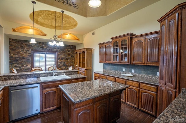 kitchen with dishwasher, a raised ceiling, sink, decorative light fixtures, and a kitchen island