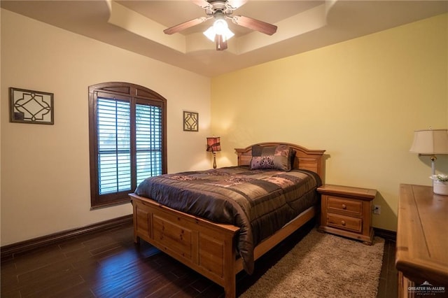 bedroom featuring a raised ceiling, ceiling fan, and dark hardwood / wood-style floors