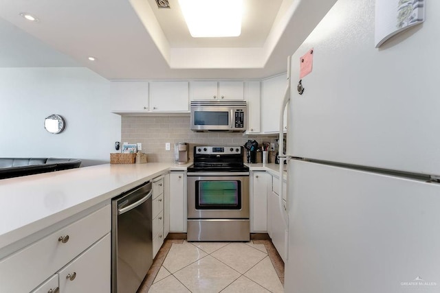 110 Padre Blvd Unit 603, South Padre Island, TX 78597 - kitchen with tasteful backsplash, stainless steel appliances, light countertops, light tile patterned floors, and a raised ceiling