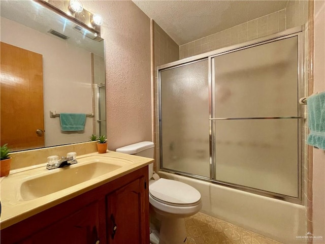 full bathroom featuring shower / bath combination with glass door, vanity, a textured ceiling, and toilet