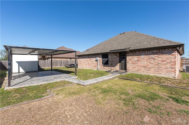 back of house featuring a patio, brick siding, roof with shingles, and a fenced backyard