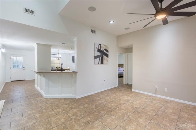 spare room with baseboards, visible vents, and ceiling fan with notable chandelier