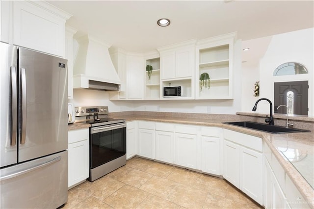 kitchen with appliances with stainless steel finishes, premium range hood, white cabinetry, open shelves, and a sink