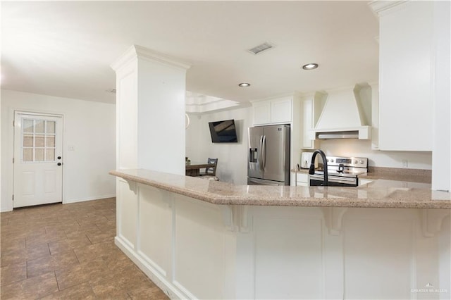 kitchen with appliances with stainless steel finishes, premium range hood, a breakfast bar area, and light stone countertops