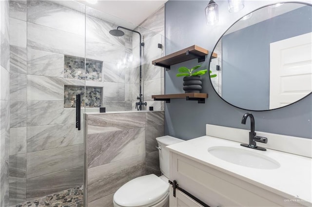 bathroom with tiled shower, vanity, and toilet