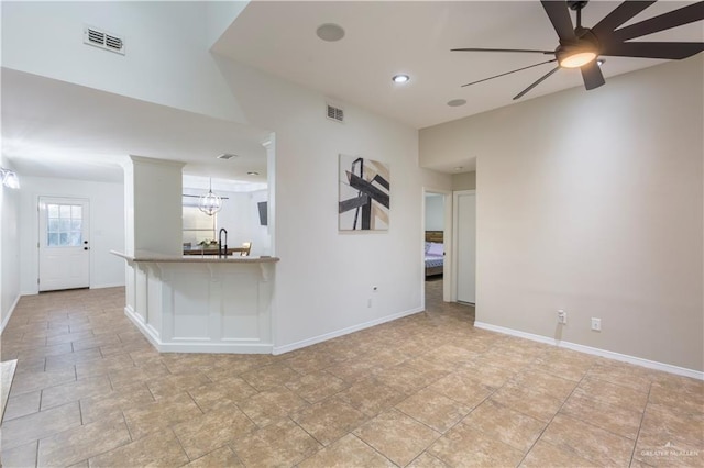 spare room featuring ceiling fan with notable chandelier, visible vents, and baseboards