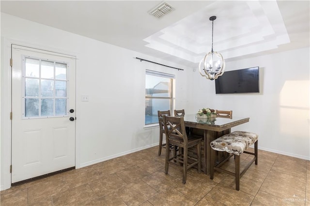 dining area featuring a tray ceiling, plenty of natural light, visible vents, and a notable chandelier