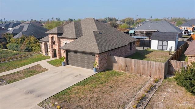 view of front facade featuring an outbuilding, concrete driveway, an attached garage, a front yard, and fence private yard