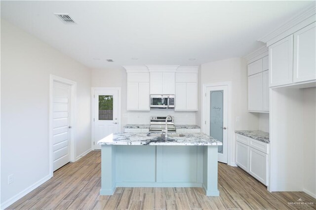 1120 Washington Ave, Mission, TX 78572 - kitchen with stainless steel appliances, light wood-style flooring, a sink, and a center island with sink