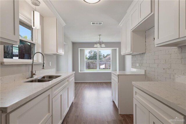 2310 Arbor St, Harlingen, TX 78552 - kitchen with a sink, light stone counters, dark wood finished floors, and white cabinetry
