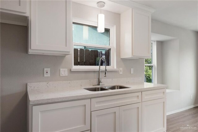 2310 Arbor St, Harlingen, TX 78552 - kitchen with a sink, white cabinets, light wood-style floors, and light stone counters